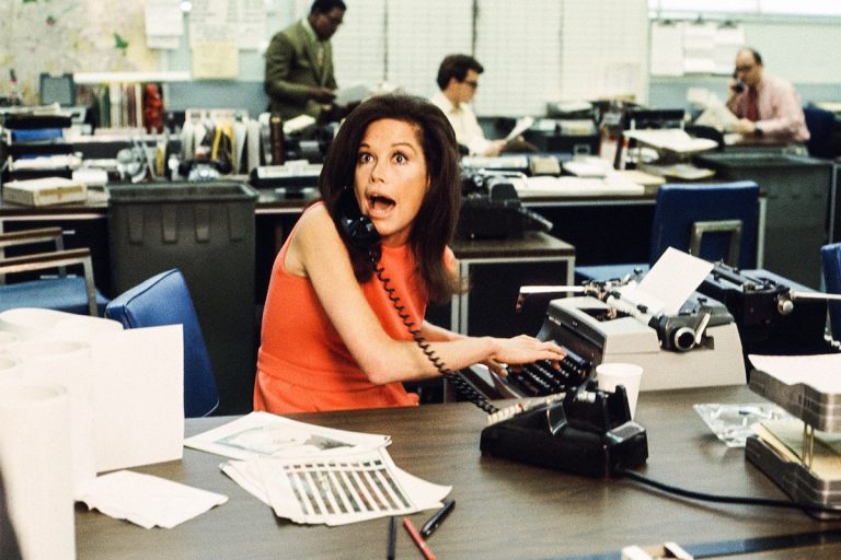 Woman at office desk on phone with a shocked look on her face